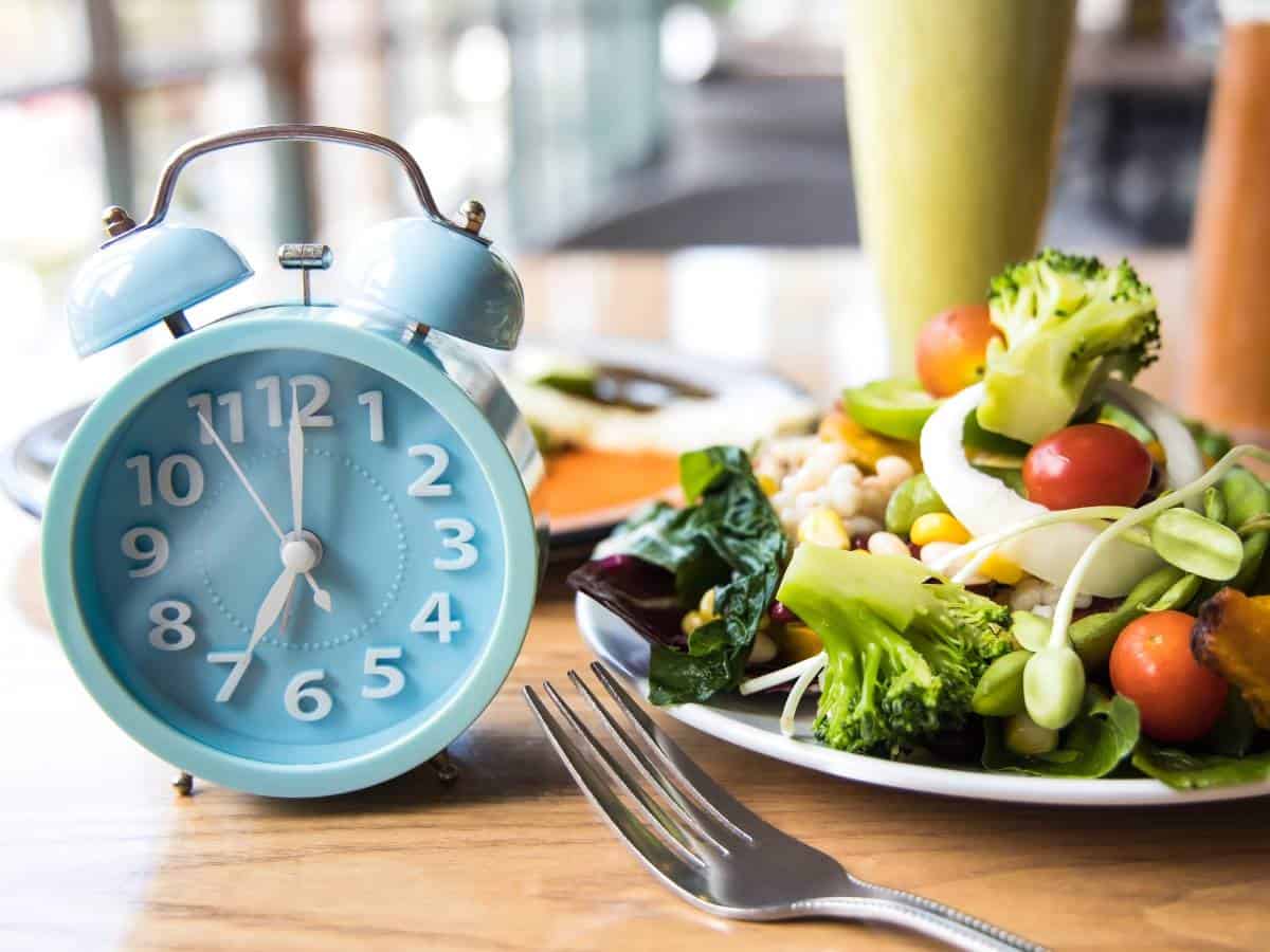 A plate of salad next to an alarm clock